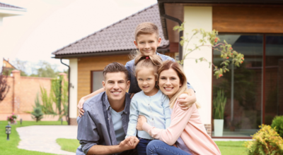 Famille souriante devant maison bois